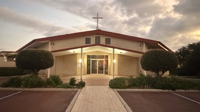 Bunbury Catholic Diocese church building with landscaped front and sunset sky.