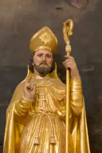 Gold-painted religious statue of a bishop with a staff and a blessing gesture.