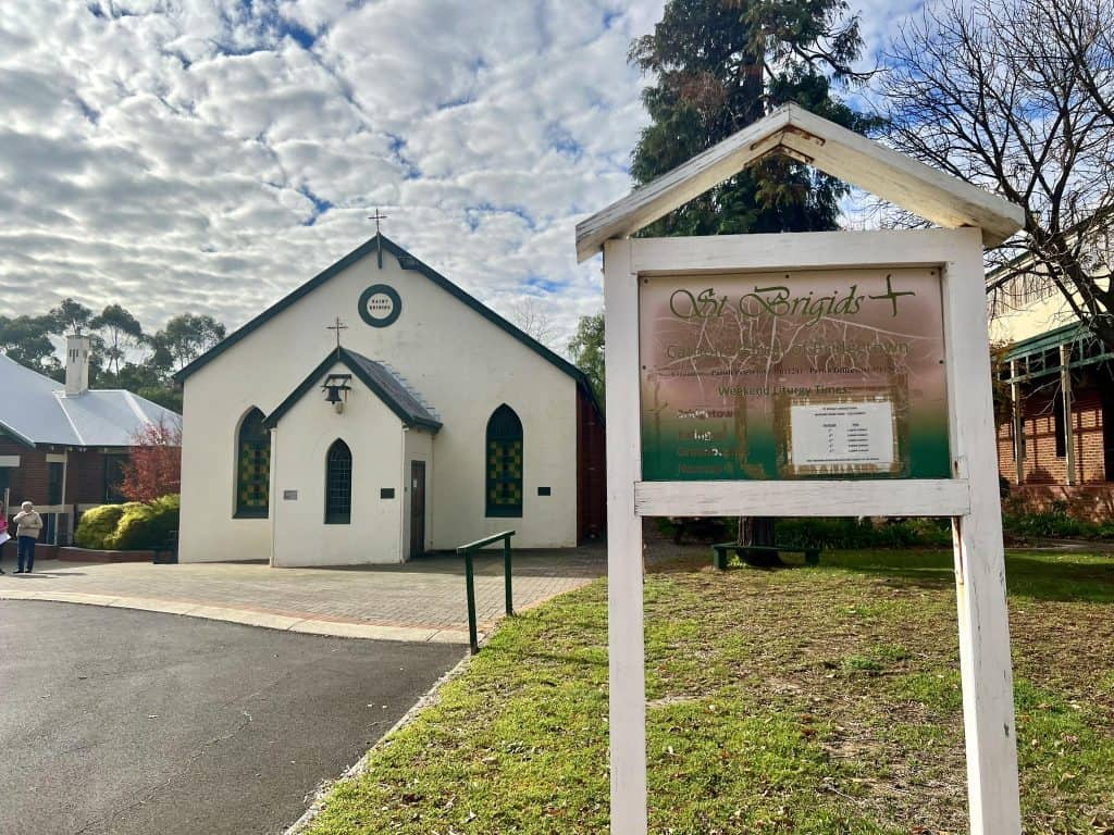 Small white church with a cross and stained glass windows in Bunbury, Australia.