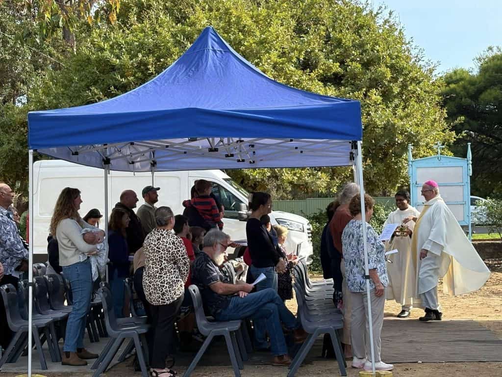 Community gathering at Bunbury Catholic Diocese outdoor event under a blue canopy.