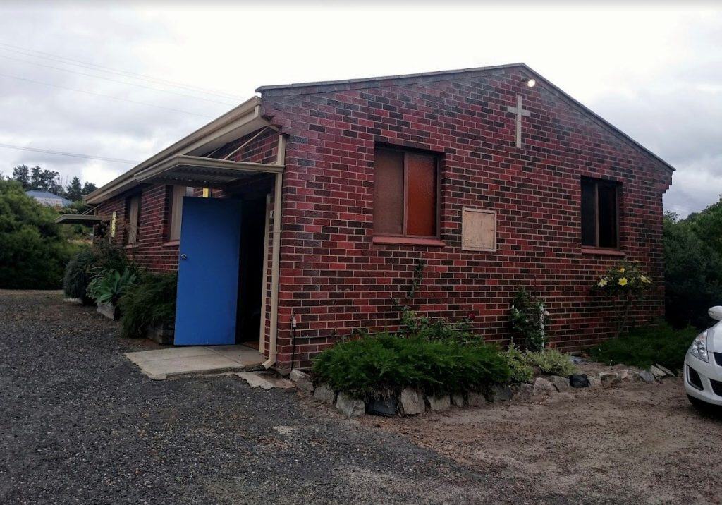 Brick church building with a cross and blue door in Bunbury, Australia.
