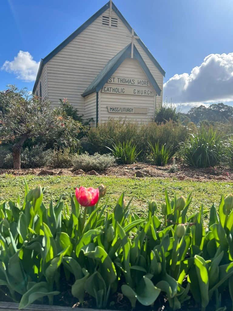 St Thomas More Catholic Church in Bunbury with blooming garden in foreground.